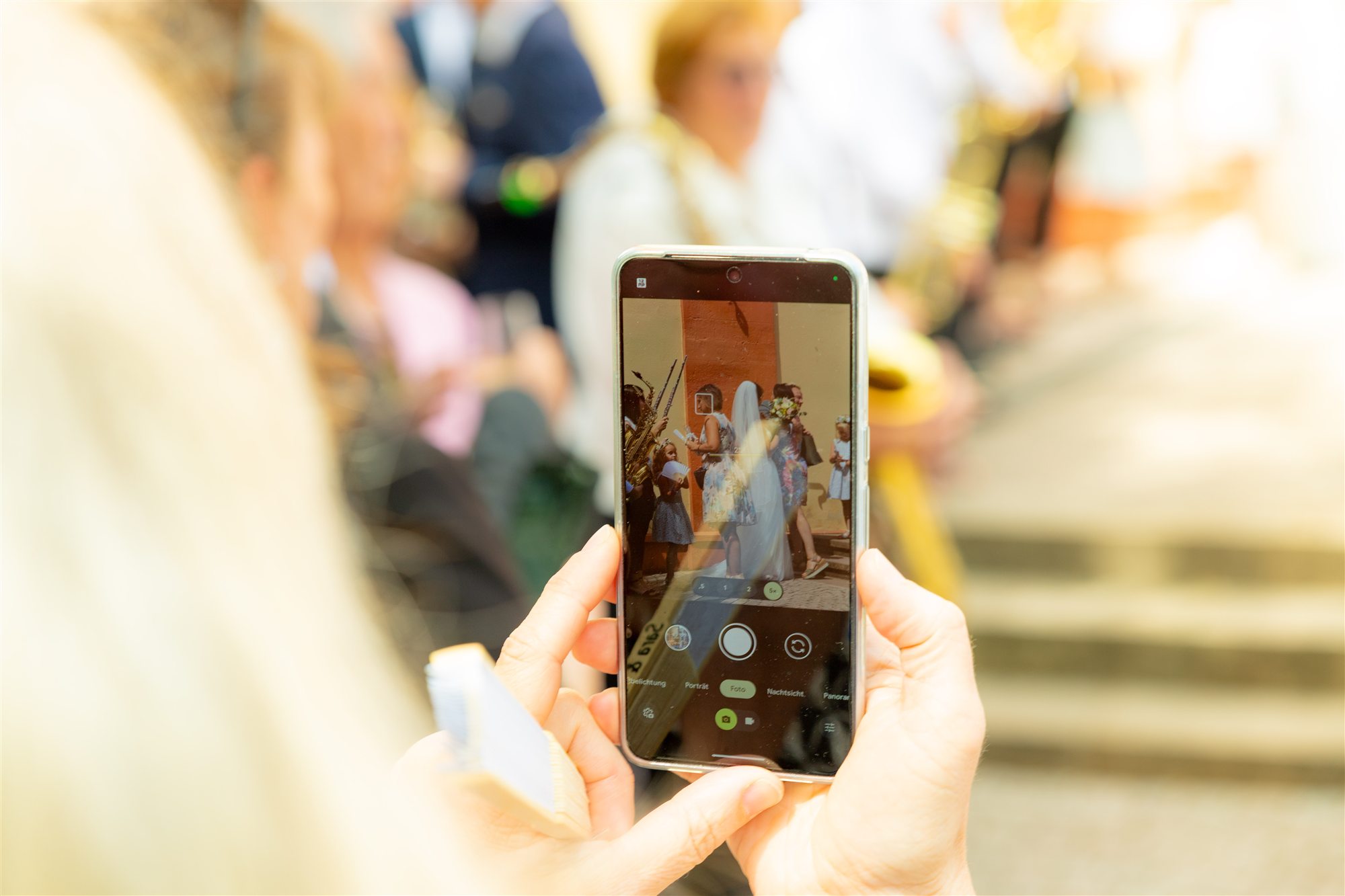 Hochzeitsgast fotografiert die Braut mit dem Smartphone