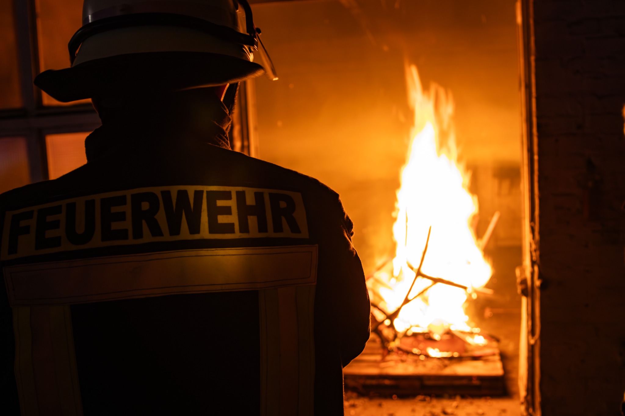 Feuerwehrperson vor einem Übungsfeuer
